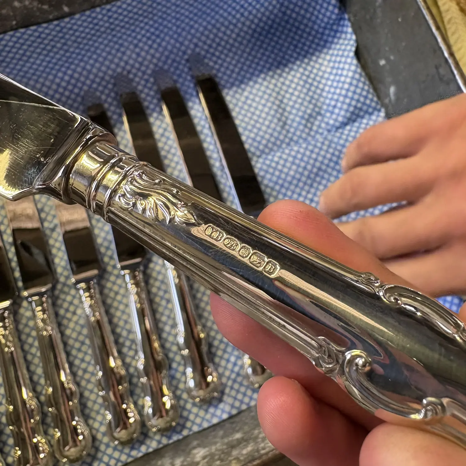 Close inspection of a custom silver cutlery handle and hallmark